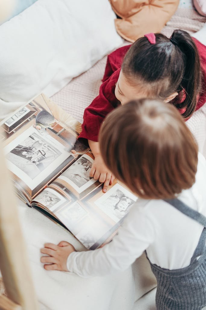 Two children enjoying a photo book on a bed, highlighting family and education themes.